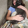 child, cat, glasses, blanket, couch, sleeping, hugging, indoor, cozy, comfort, furniture, relaxing, pet, animal, young_person, casual_clothing, rest, soft_texture, affection, peaceful