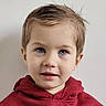 blue_eyes, child, closeup, cute, face, head, hoodie, indoor, looking_up, maroon_hoodie, person, plain_wall, portrait, short_hair, skin, smile, teeth, toddler, wet_hair, young_child