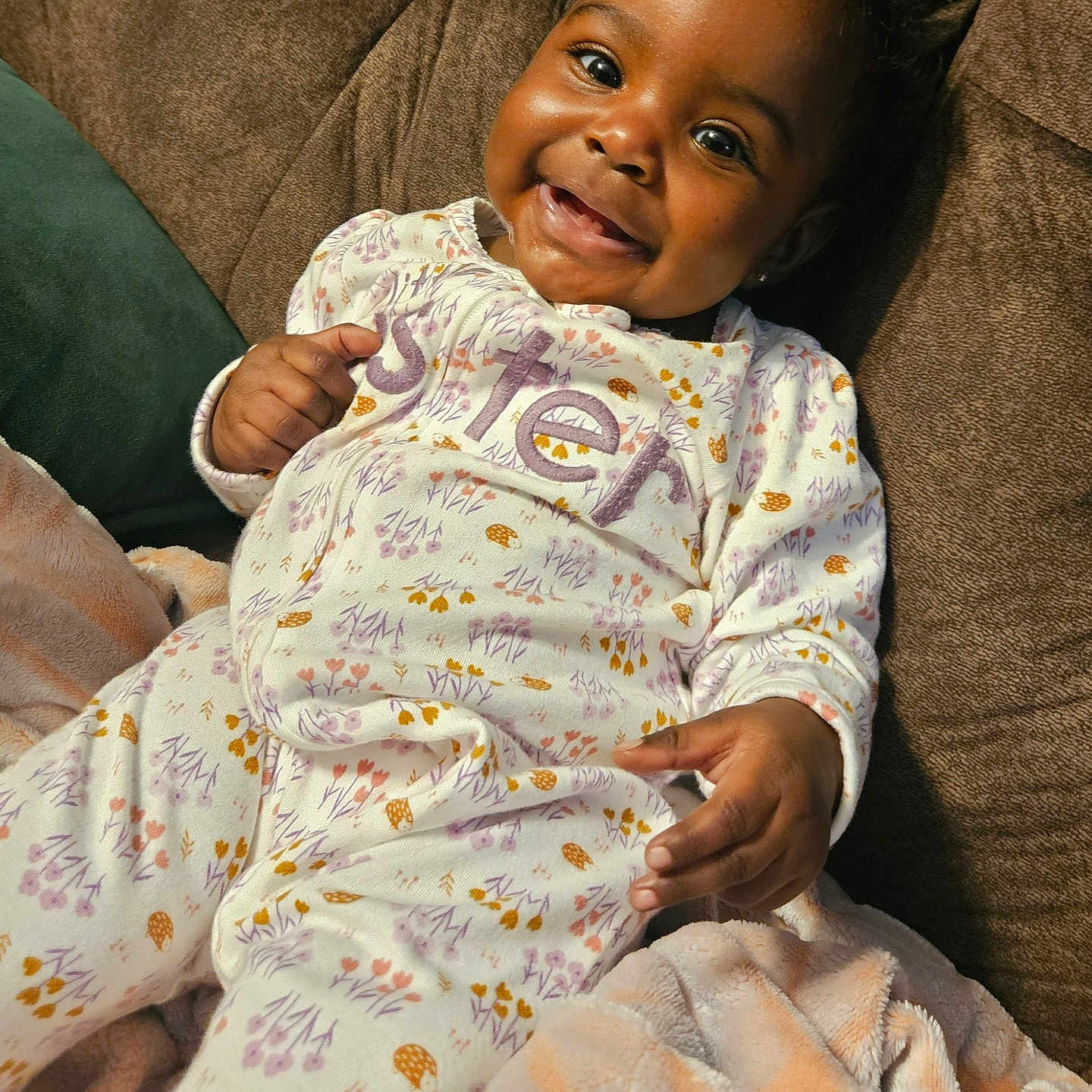 Dehlani is registered to the contest to win money with this photo: baby, blanket, child, comfort, couch, cozy, cute, expression, furniture, happy, indoors, infant, onesie, person, portrait, relaxed, seated, smiling, soft, warm