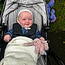 Maggie is registered to the contest to win money with this photo: baby, stroller, blanket, plush_toy, bunny, bonnet, child, outdoor, greenery, flowers, purple_flowers, grass, happy, smile, person, clothing, baby_clothes, toy, nature, park