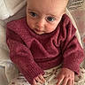 baby, infant, child, sweater, floral_pants, sitting, cushion, seat, blue_eyes, cute, cozy, indoors, warning_label, hands, feet, socks, soft_texture, portrait, young_child, curious