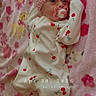 baby, infant, pink_headband, pacifier, onesie, cherry_pattern, blanket, floral, cute, newborn, sleepwear, lying_down, indoors, soft_texture, adorable, child, portrait, headband, bedtime, comfort