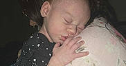 Meadow joined the competition — help win amazing prizes! baby, sleeping, infant, person, child, holding, dark_background, floral_clothing, hand, head, face, closeup, toddler, black_outfit, patterned_clothing, peaceful, resting, indoor, caring, hug