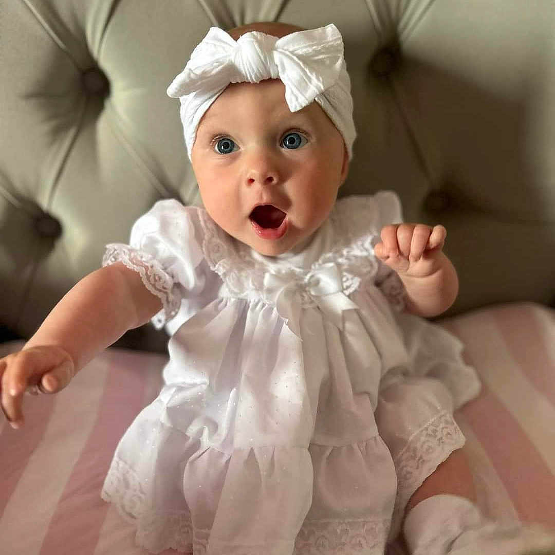 Madison is registered to the contest to win money with this photo: baby, bonnet, clothing, face, hat, head, person, photography, portrait, sitting, surprised, yawning