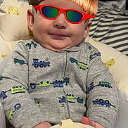 Layton joined the competition — help win amazing prizes! baby, child, cushion, clothing, container, toy, bottle, face, glasses, digital_filter, wig, hand, indoor, seated, comfort, pattern, cute, smile, background, room