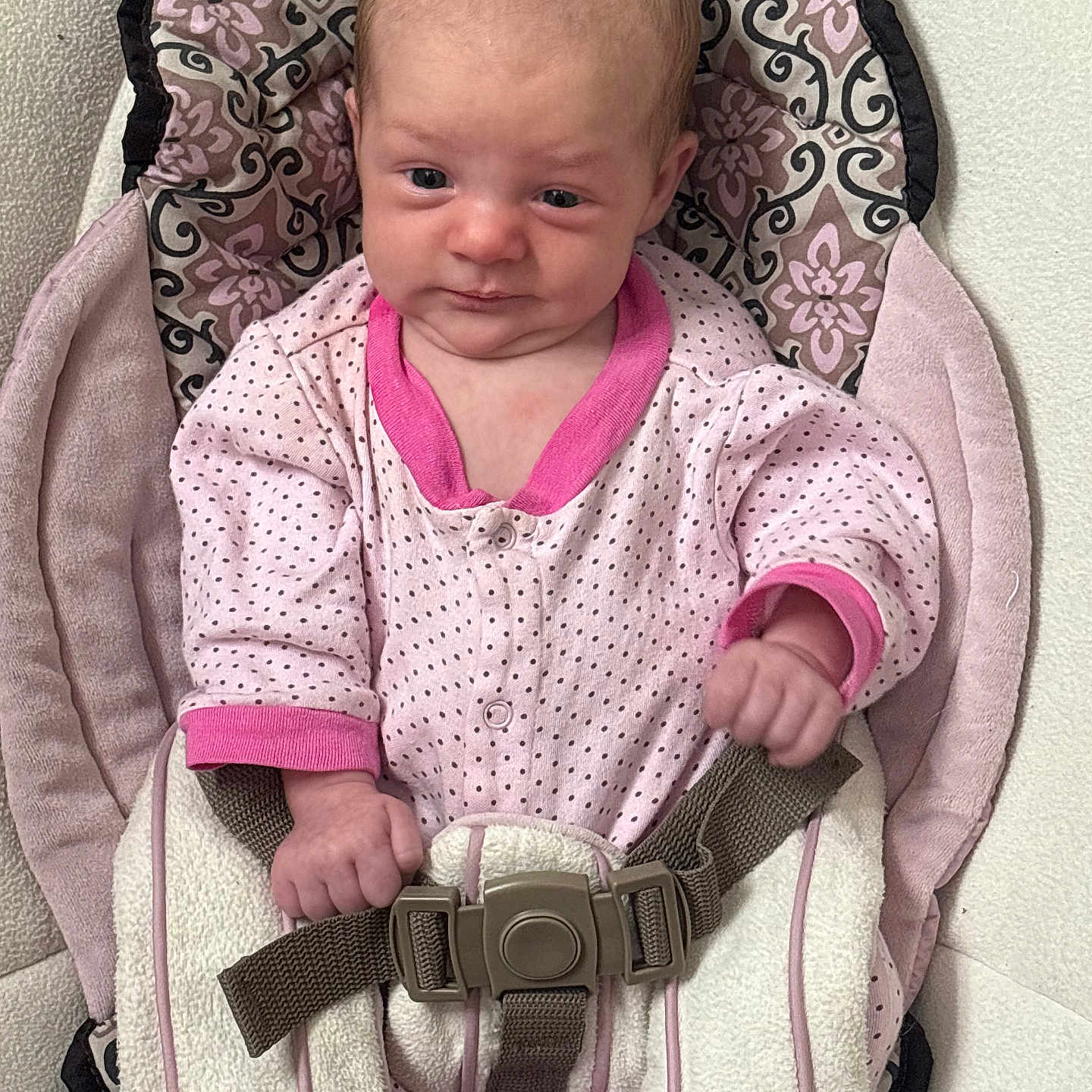 Evelynn is registered to the contest to win money with this photo: baby, baby_seat, child, cushion, cute, expression, fabric, face, hand, indoor, infant, newborn, onesie, pattern, person, pink_clothing, polka_dot, safety_strap, seat, small