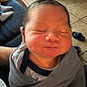 Tommy is registered to the contest to win money with this photo: newborn, baby, infant, wrapped, blanket, sleeping, face, closed_eyes, person, hand, floor, tile, footwear, sandal, indoor, cozy, soft, young_child, portrait, resting