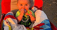 Nolan is registered to the contest to win money with this photo: baby, pacifier, quilt, stroller, outdoor, sunset, child, blanket, colorful, red, path, nature, infant, cute, warm_light, portrait, young_child, clothing, smiling, sitting
