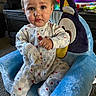 Nolan is registered to the contest to win money with this photo: baby, child, toddler, pajamas, plush_chair, toy, lollipop, indoor, carpet, furniture, face, person, cute, expression, star_pattern, hand, sitting, colorful, home, room