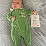 baby, blanket, card, child, clothing, cute, expression, face, footed_pajamas, green_onesie, hand, indoor, infant, lying_down, newborn, person, portrait, soft, texture, two_months