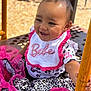 baby, child, smiling, pink, bib, crown, hair_clip, leopard_print, playground, outdoor, sunny, happy, dress, clothing, hand, yellow_bar, sitting, person, cute, infant