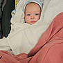 Kato is registered to the contest to win money with this photo: baby, infant, swaddled, towel, blanket, car_seat, stroller, hat, face, eyes, portrait, cute, looking_at_camera, cozy, wrapped, pink_cloth, white_towel, human, indoors, small_person