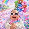 baby, child, sunglasses, smiling, happy, colorful, rainbow, clouds, hearts, care_bears, plush_toys, cute, fun, joyful, portrait, fantasy_background, cartoon_characters, playful, infant, clothing