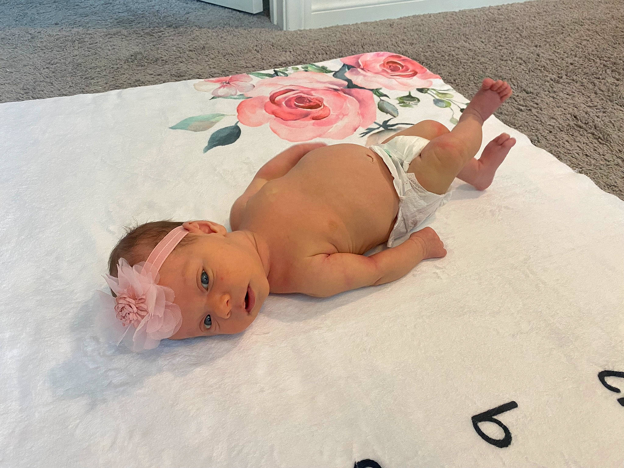 Brooklyn is registered to the contest to win money with this photo: baby, barechested, bed, bed_sheet, bedding, child, comfort, finger, flower, hat, headpiece, headwear, human_leg, linens, person, petal, pink, rose, sand, skin