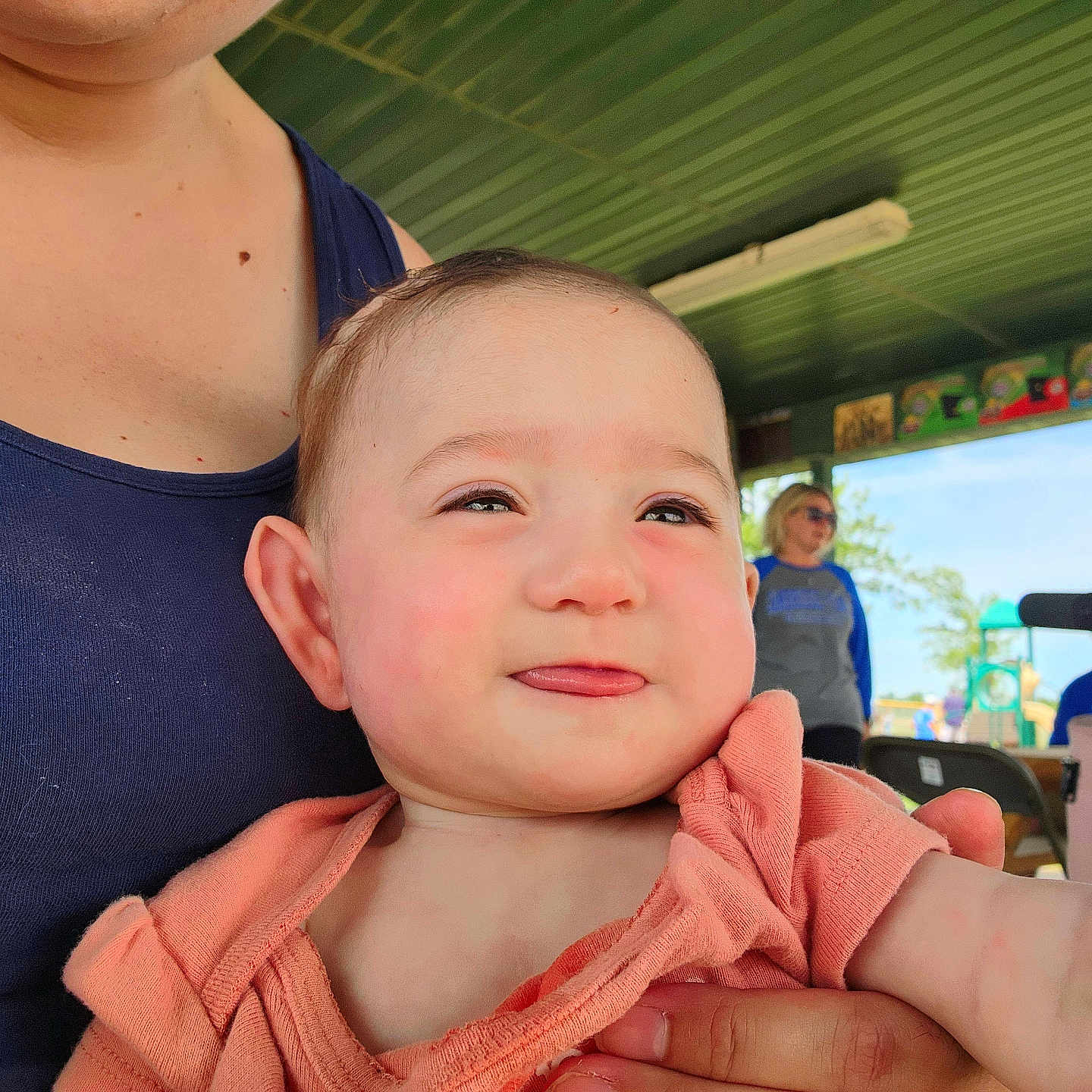 Freya joined the competition — help win amazing prizes! adult, baby, background, casual, child, clothing, daylight, face, hand, happy, holding, outdoor, people, person, playground, roof, skin, smile, tank_top, tongue