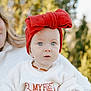 baby, child, red_bow, headband, sweater, my_first_christmas, holiday, portrait, outdoor, nature, blue_eyes, knitwear, cute, infant, person, face, smile, winter_clothing, necklace, family