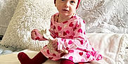 Alexis joined the competition — help win amazing prizes! toddler, child, girl, heart_pattern, dress, red_tights, red_bow, headband, giraffe_toy, sofa, pillows, blanket, indoor, cute, smiling, portrait, cozy, comfort, baby, seated