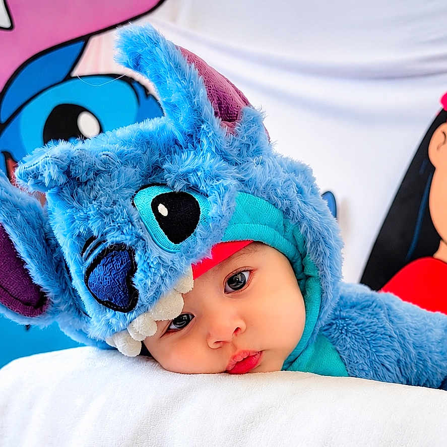 Kai joined the competition — help win amazing prizes! baby, child, costume, blue, plush, face, portrait, cute, expression, headwear, soft, resting, indoor, colorful, character, disney, stitch, clothing, person, closeup