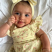 Meliha is registered to the contest to win money with this photo: baby, child, infant, headband, bow, yellow, dress, floral, smile, face, hand, pacifier, white_background, soft_texture, cute, portrait, closeup, resting, happy, indoors