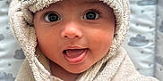 Meliha is registered to the contest to win money with this photo: baby, child, towel, hooded_towel, face, eyes, mouth, tongue, hand, skin, fabric, cute, infant, wrapped, soft, plush, background, clouds, pattern, adorable