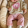 baby, smiling, infant, child, headband, pink_clothing, beige_clothing, socks, baby_chair, cushion, happy, indoors, portrait, cute, cozy, soft_texture, floor, person, seated, young_child