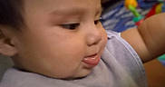 Bryson is registered to the contest to win money with this photo: baby, child, face, tongue, bib, clothing, indoor, furniture, couch, toy, curious, closeup, person, head, skin, expression, young, infant, home, casual