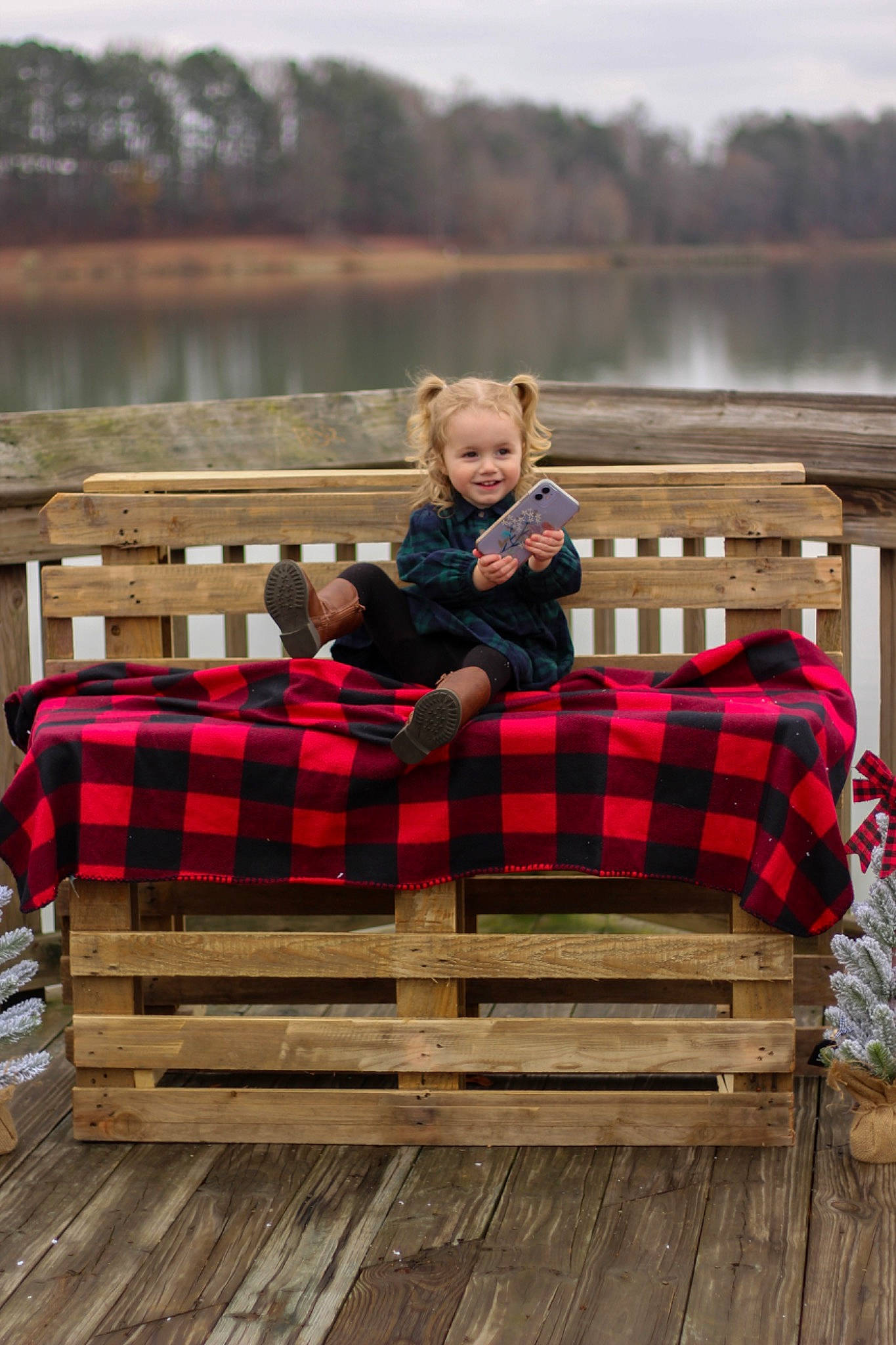Maisyn is registered to the contest to win money with this photo: comfort, grass, hardwood, joy, lake, lap, leisure, morning, outdoor_furniture, pattern, person, plaid, recreation, sitting, sky, table, tartan, toddler, tree, vacation