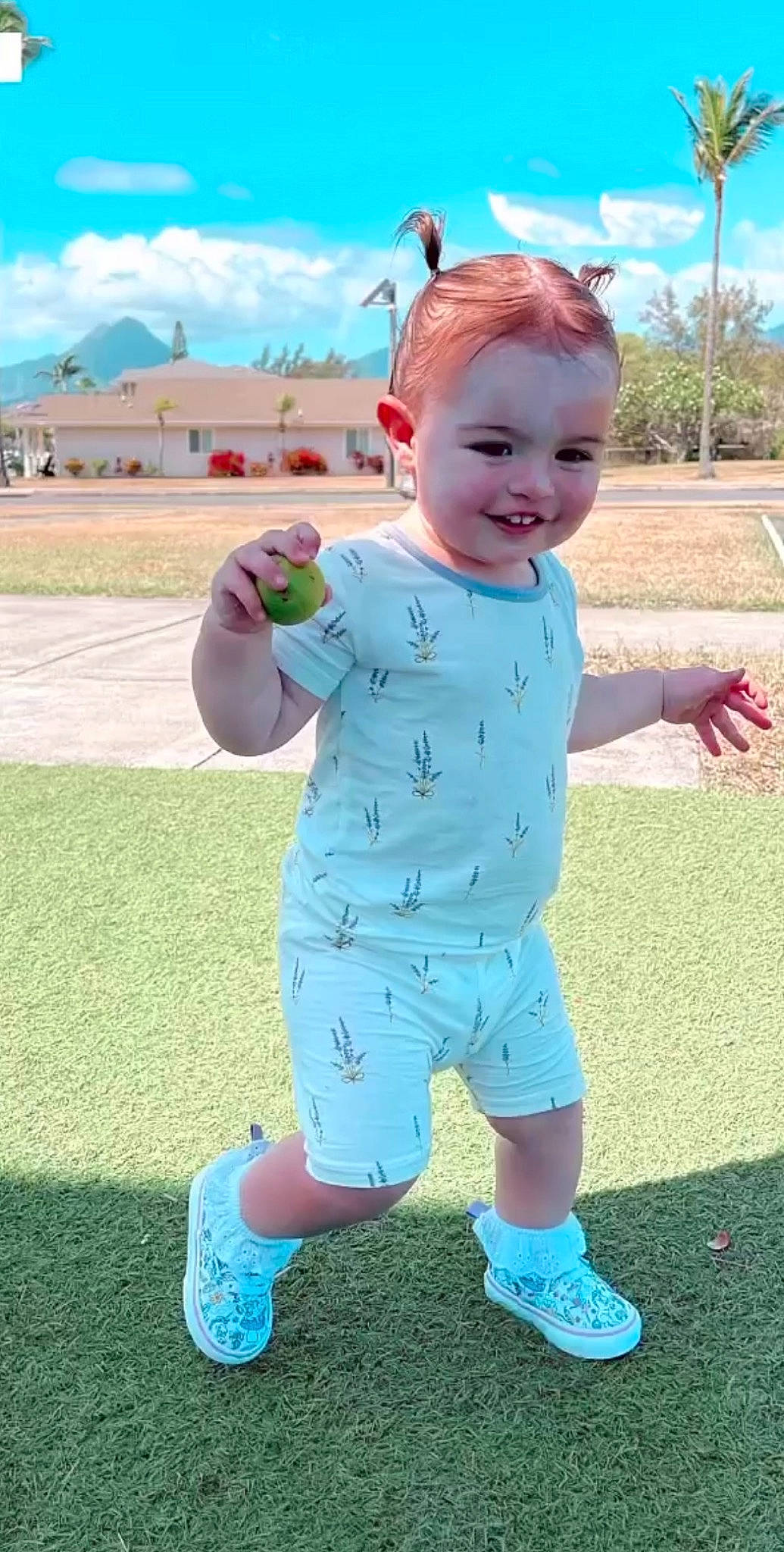 Arabella is registered to the contest to win money with this photo: baby, baby_toddler_clothing, blue, cloud, face, finger, fun, gesture, grass, hand, happy, joy, leisure, people_in_nature, person, pink, recreation, sky, sleeve, smile