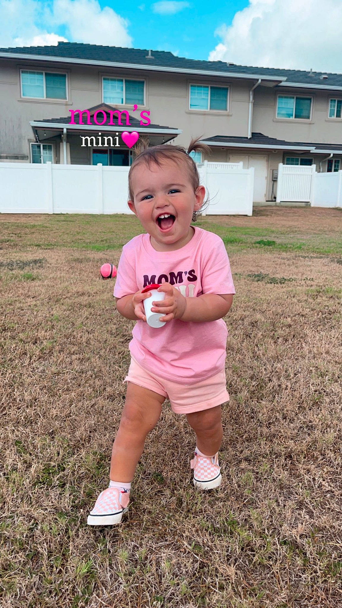 Arabella is registered to the contest to win money with this photo: baby_toddler_clothing, building, cloud, fun, grass, happy, house, leisure, magenta, people_in_nature, person, pink, plant, recreation, shoe, shorts, sky, sleeve, smile, toddler