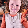 autumn, background, buttoned_vest, child, curly_hair, cute, face, festive, girl, happy, hay, indoor, orange_shirt, person, portrait, pumpkins, seasonal, smiling, standing, vest