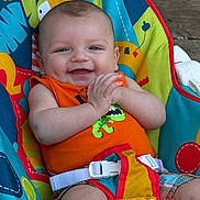 Brady is registered to the contest to win money with this photo: baby, infant, child, smile, smiling, baby_seat, colorful, orange_shirt, dinosaur_print, safety_buckle, hands, feet, portrait, outdoor, wooden_background, happy, cheerful, seat_cover, close_up, chubby_cheeks