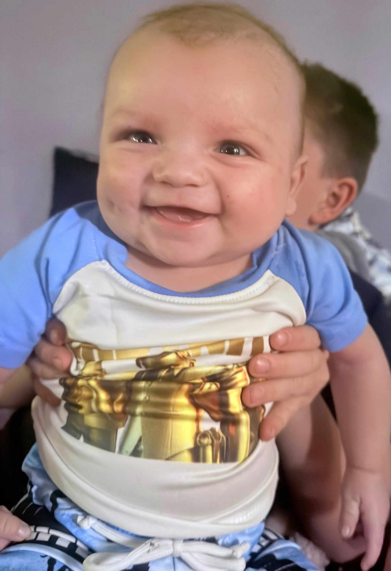 Brady joined the competition — help win amazing prizes! baby, infant, child, smiling, dimples, cheeks, face, eyes, hands, sibling, onesie, blue_clothing, closeup, portrait, indoor, happy, person, holding, skin, ear