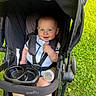 Sterlin is registered to the contest to win money with this photo: baby, child, stroller, evenflo, grass, outdoor, bottle, smile, blue_eyes, sitting, clothing, harness, happy, person, infant, toy, seat, sunlight, nature, portrait