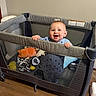 Sterlin joined the competition — help win amazing prizes! baby, playpen, toy, smiling, child, indoor, blue_clothing, happy, standing, wooden_floor, mesh_sides, infant, home, cute, person, play_area, flooring, furniture, bright, childcare