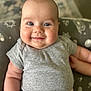 baby, smiling, blue_eyes, gray_shirt, pink_pants, chubby_cheeks, infant, cushion, patterned, close_up, portrait, happy, cute, skin, person, child, indoor, soft_lighting, seated, young