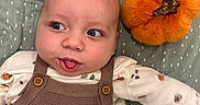 Anthony is registered to the contest to win money with this photo: baby, bed, blanket, brown_hair, child, closeup, clothing, cute, indoor, infant, lying_down, onesie, open_mouth, orange_toy, overalls, plush_toy, polka_dots, portrait, smiling, wide_eyed