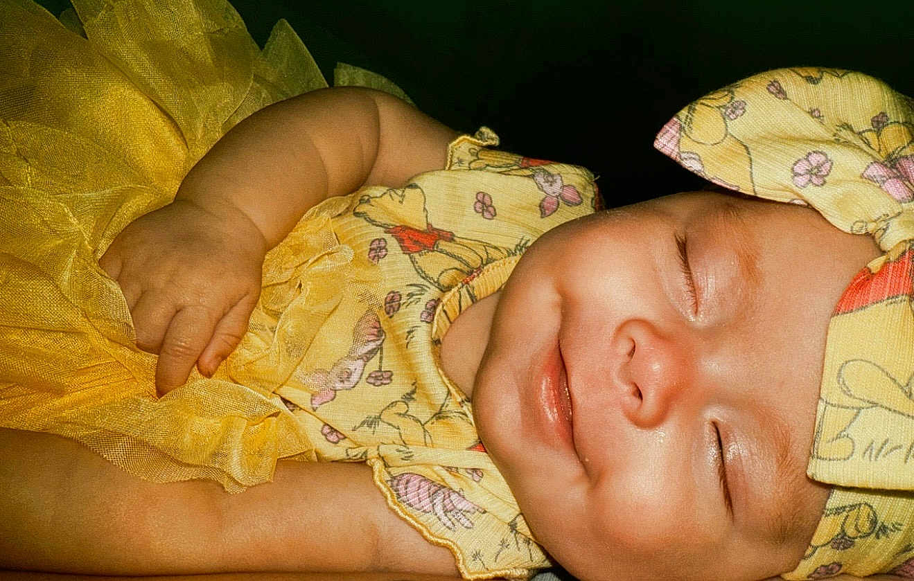 Amaya joined the competition — help win amazing prizes! baby, sleeping, smile, yellow_dress, headband, child, infant, closeup, cute, peaceful, portrait, soft_lighting, skin, chubby_arm, fabric, pattern, flower, happy, resting, adorable