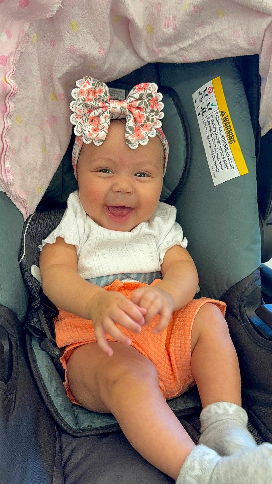 Jaslin joined the competition — help win amazing prizes! baby, child, smiling, car_seat, headband, bow, orange_shorts, white_shirt, blanket, happy, infant, socks, hands, face, seatbelt, indoors, cute, person, portrait, car