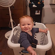 Braylyn is registered to the contest to win money with this photo: toddler, child, laundry_basket, smiling, indoor, fan, dresser, clothing, floor, household, toy, person, baby, happy, reaching, furniture, room, plastic, basket, cute