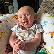 Noah joined the competition — help win amazing prizes! baby, infant, smiling, happy, blue_eyes, onesie, animal_print, cushion, monkey, giraffe, elephant, tiger, green_toy, indoor, portrait, cute, child, person, seated, playful