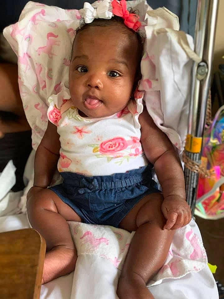 Ka'Miya is registered to the contest to win money with this photo: baby, baby_products, baby_toddler_clothing, cheek, child, embellishment, eye, hair_accessory, headband, headpiece, mouth, nose, person, pink, sitting, sock, toddler