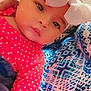 baby, child, headband, bow, red_clothing, polka_dots, patterned_fabric, close_up, curly_hair, portrait, indoor, person, cute, infant, face, eyes, soft_lighting, resting, pink, blue