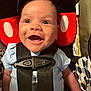 baby, infant, car_seat, happy, smile, straps, clothing, blue_shirt, headrest, plush, child, person, seat_belt, indoor, closeup, cute, face, safety, infant_seat, joy