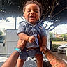 Sincere is registered to the contest to win money with this photo: baby, child, smiling, happy, curly_hair, blue_outfit, tattooed_arms, sandals, outdoor, tree, car, street, daylight, person, holding, portrait, cute, infant, sunlight, standing