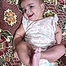 Yashfa is registered to the contest to win money with this photo: baby, smiling, infant, lying_down, onesie, foot, carpet, patterned, colorful, cheerful, child, cute, playful, indoors, young, person, happy, skin, head, expression
