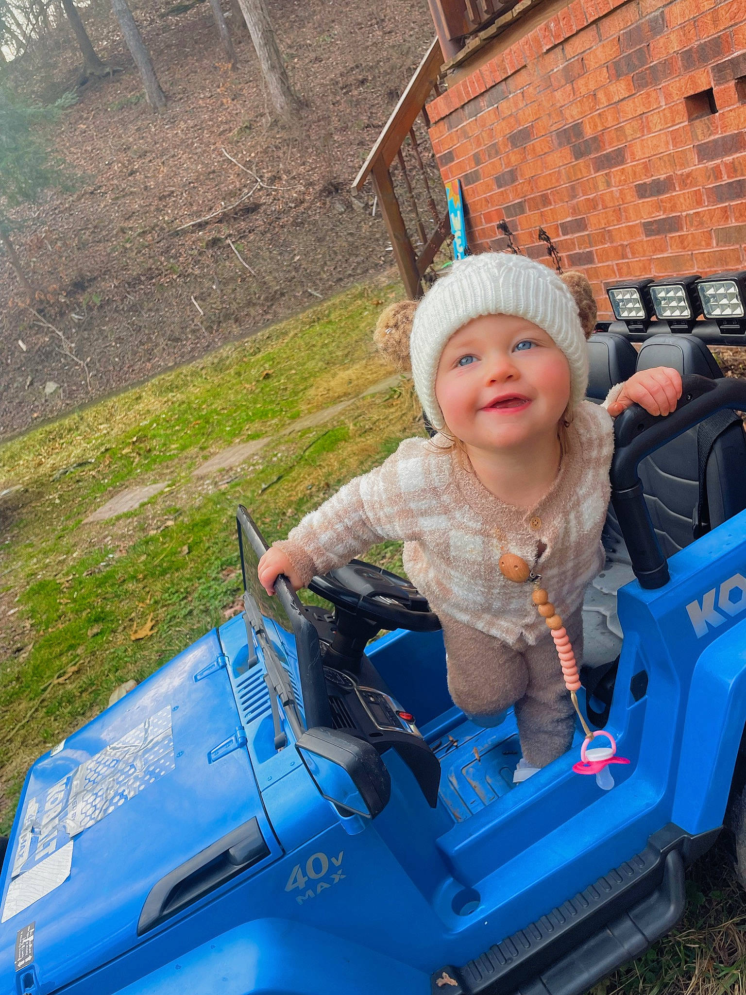 Harper is registered to the contest to win money with this photo: automotive_design, automotive_exterior, automotive_tire, automotive_wheel_system, baby_toddler_clothing, bumper, fender, grass, headwear, helmet, hood, joy, leisure, motor_vehicle, person, plant, recreation, riding_toy, smile, tire