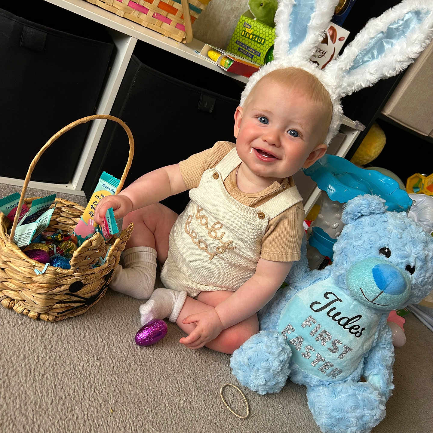 Jude is registered to the contest to win money with this photo: baby, basket, blue, bunny_ears, carpet, celebration, child, clothing, cute, easter, gift, happy, holiday, indoor, pastel_colors, person, plush, smiling, teddy_bear, toy