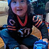 Sebastian is registered to the contest to win money with this photo: child, toddler, blue_beanie, sports_jersey, toy_dinosaur, wooden_floor, christmas_tree, holiday_decorations, indoor, smiling, curly_hair, casual_clothing, playtime, happy, floor, feet, socks, home, festive, fun