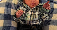 William is registered to the contest to win money with this photo: newborn, baby, infant, sleeping, face, portrait, plaid_shirt, jeans, blanket, checkered_blanket, pillow, couch, indoors, lying_down, closed_eyes, hand_gesture, fist, soft_lighting, cozy, family_photo