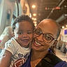 baby, infant, adult, woman, selfie, portrait, smiling, happy, family, 親子, 抱っこ, indoor, warm_lighting, glasses, curly_hair, white_shirt, purple_clothing, football_graphic, restaurant, closeup